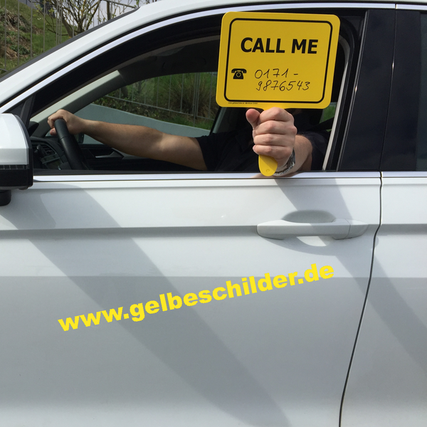 Autofahrer hält gelbes Schild mit Textaufschrift "Call Me" aus dem Fenster 