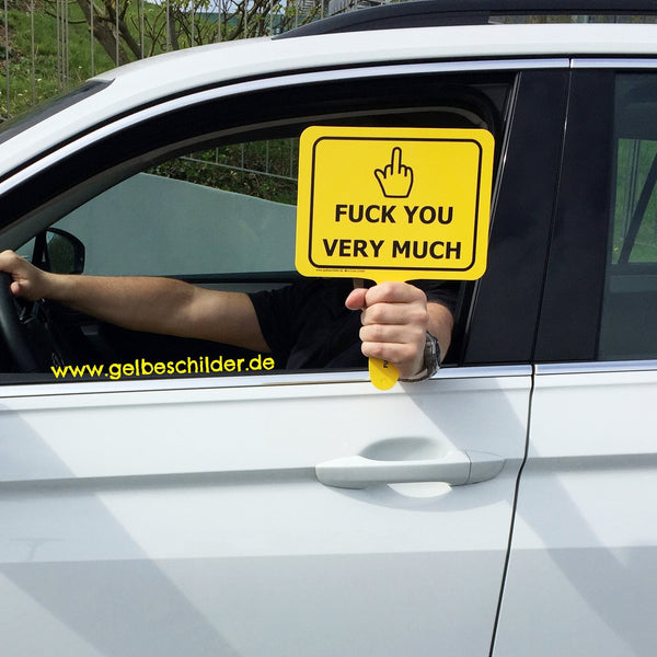 Autofahrer hält gelbes Schild mit Textaufschrift "Fuck you very much" aus dem Fenster 