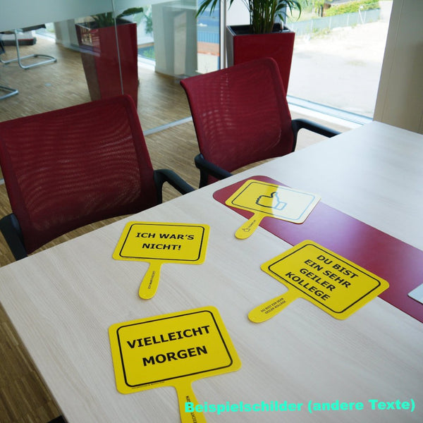 Mehrere gelbe Schilder mit lustigen Sprüchen liegen auf einem Bürotisch